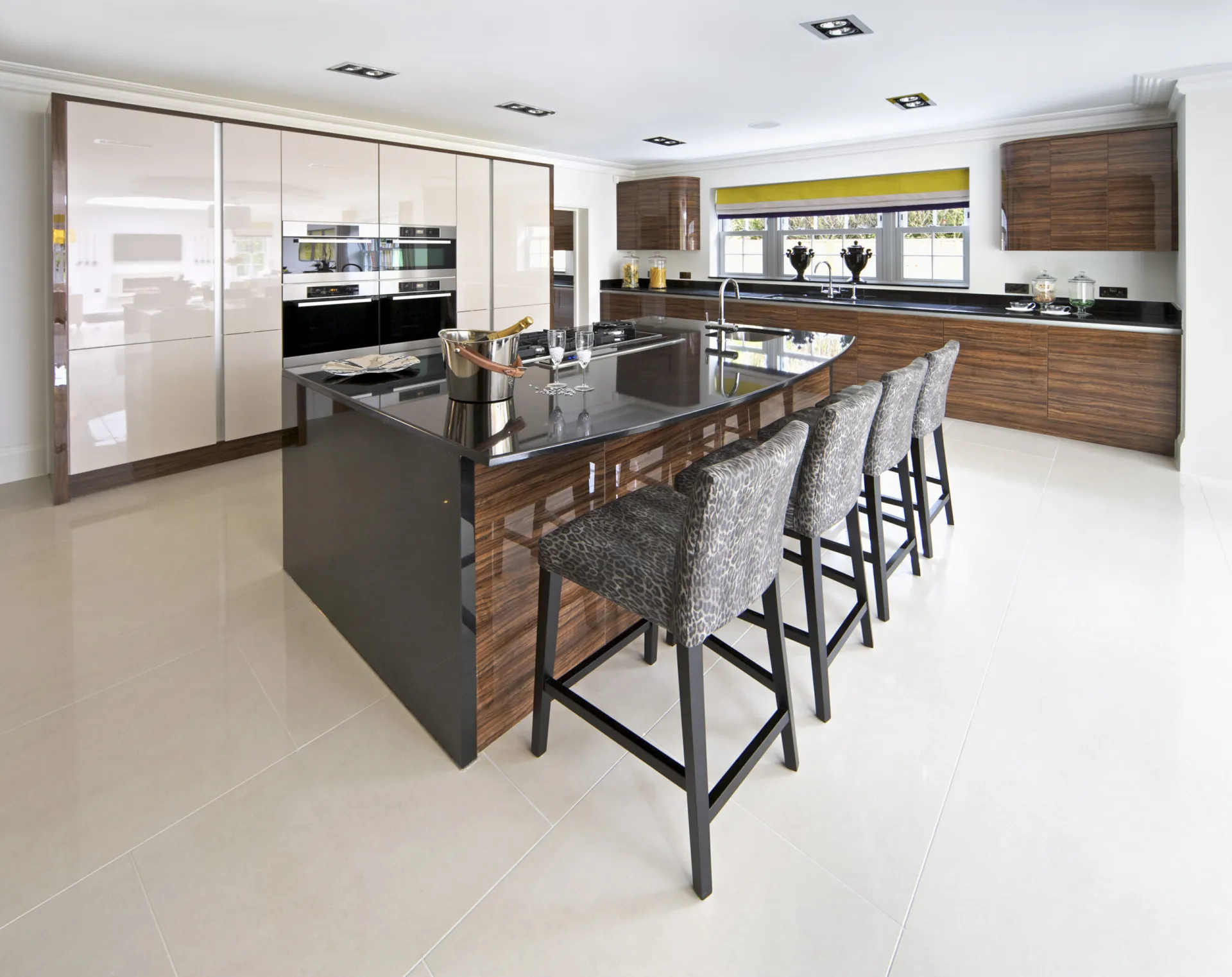 a bright and spaceous kitchen in a new luxury home. A large kitchen island is set in the centre with a large black granite top creating a breakfast bar.